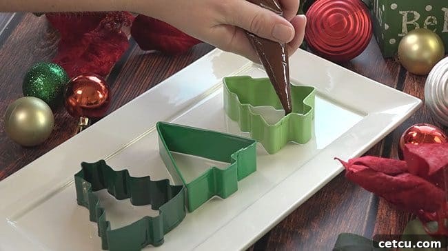 Frosted Forest Peppermint Bark 3 Ingredients and tools laid out for making Christmas Tree Peppermint Bark, including cookie cutters, chocolate, and crushed candy canes.