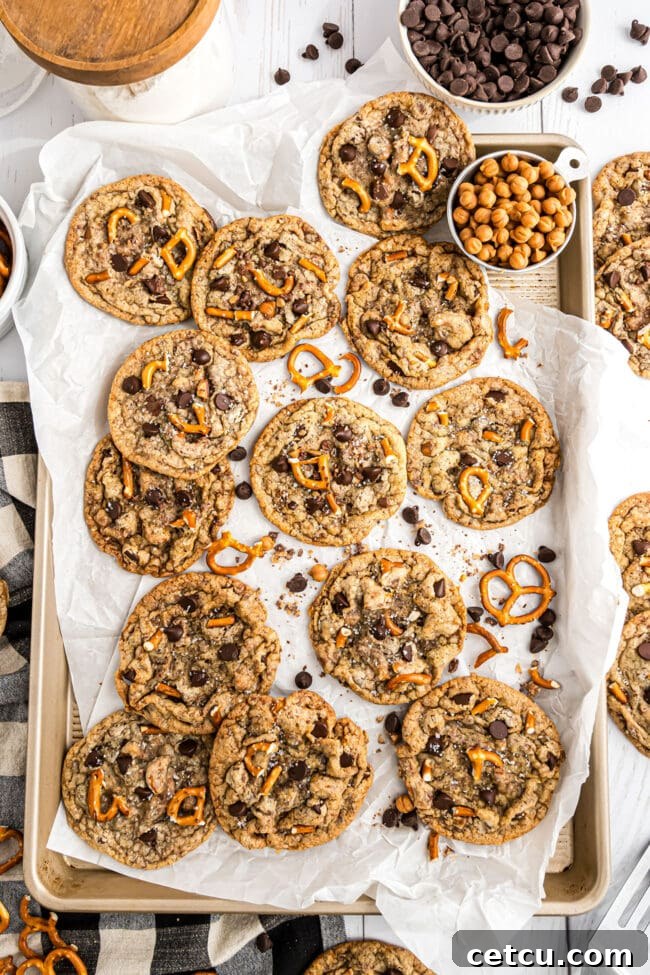 Irresistible Kitchen Sink Cookies artfully arranged on a pan with parchment paper, showcasing their rich, diverse ingredients and golden-brown perfection.