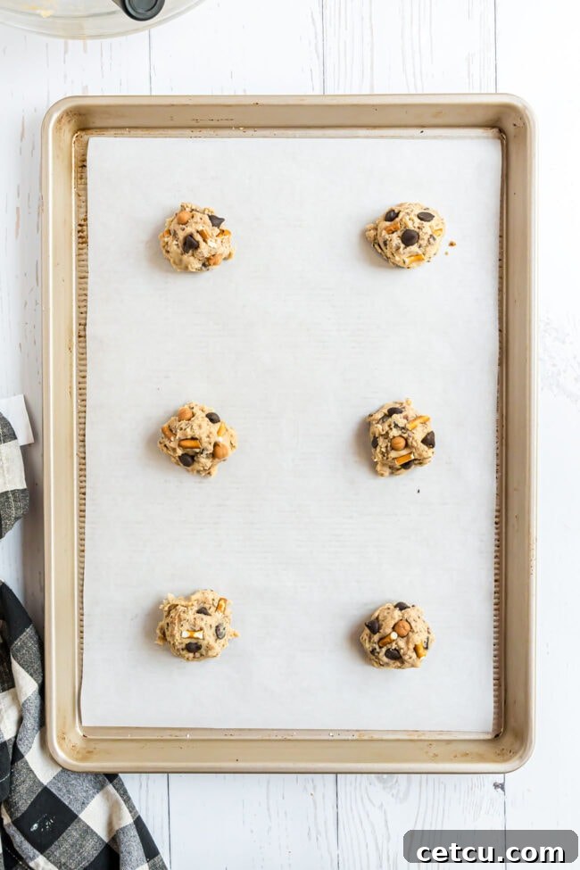 Uniformly shaped Kitchen Sink Cookies precisely placed on a baking sheet, poised for their delicious transformation in the oven.