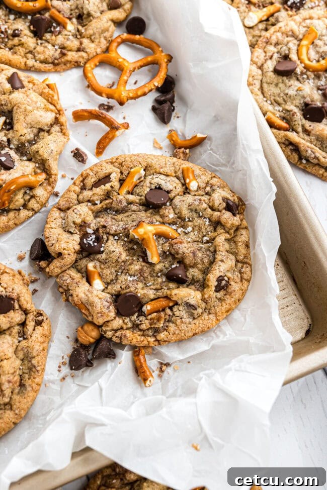 A close-up of a single Kitchen Sink Cookie, highlighting its rich textures and diverse mix-ins, perfectly showcasing its sweet and salty appeal.