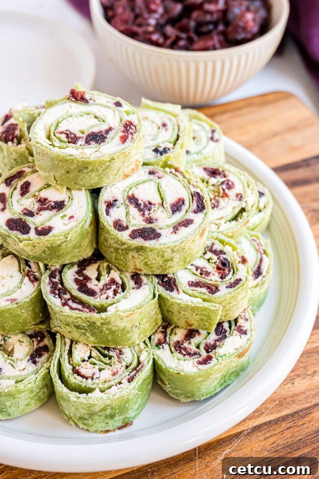 Cranberry Swirl Christmas Tree Bites 9 a plate stacked with cranberry feta pinwheels with green tortillas for the holidays