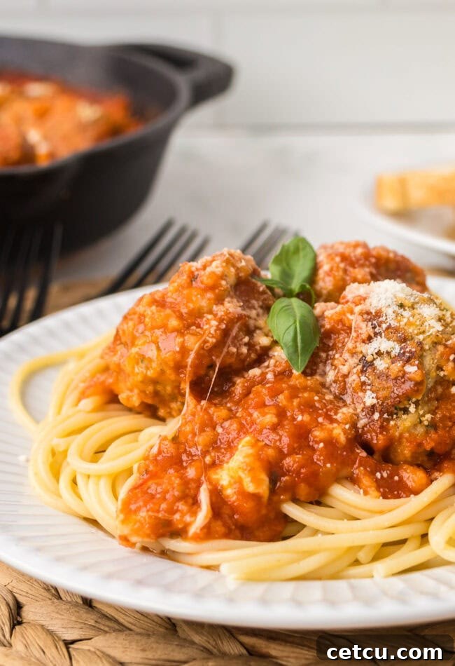 A close-up of finished chicken Parmesan meatballs in a skillet.