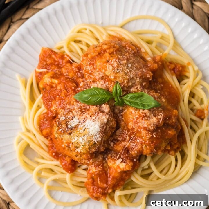 Chicken Parmesan meatballs served over spaghetti with marinara sauce, melted mozzarella, and fresh basil.