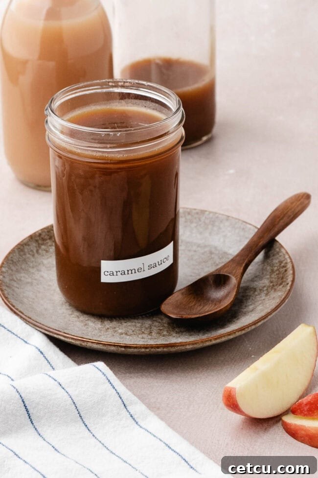 Jar of homemade salted apple cider caramel sauce with a wooden spoon.