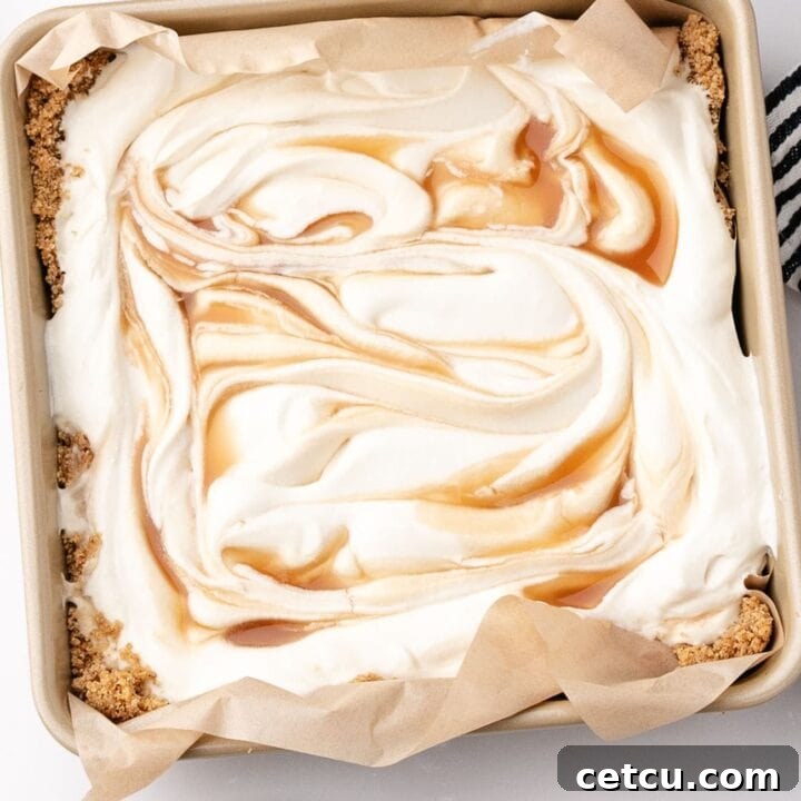 Salted caramel scoopable cheesecake with creamy filling and caramel swirls in a square baking dish