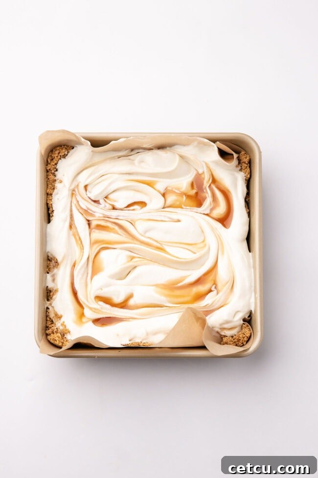Scoopable Salted Caramel Cheesecake Recipe 6 No-bake cheesecake filling topped with swirls of salted caramel in a square baking dish