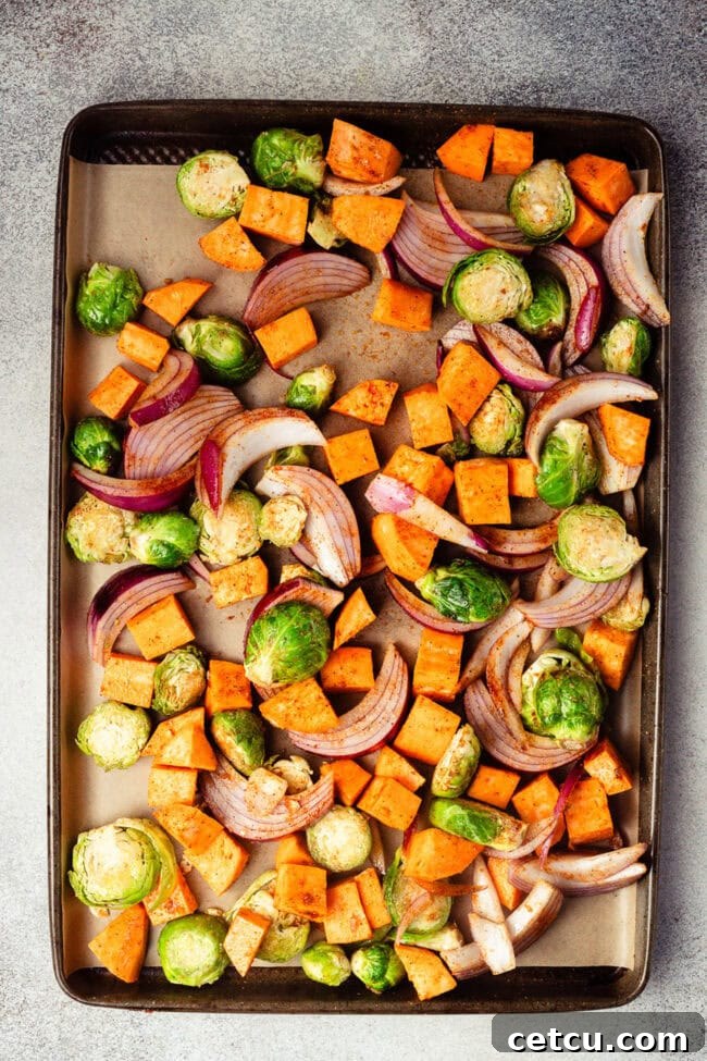 Cranberry Orange Glazed Salmon Recipe with Citrus Sauce 4 Seasoned sweet potatoes, Brussels sprouts, and red onion on a sheet pan.