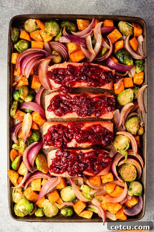 Cranberry Orange Glazed Salmon Recipe with Citrus Sauce 7 Cranberry orange glaze spooned over salmon fillets on a sheet pan.
